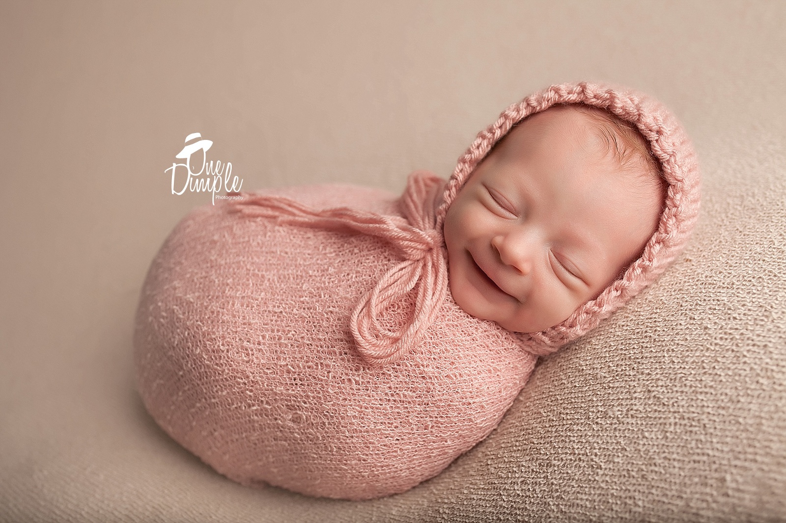 newborn in pink wrap with smile