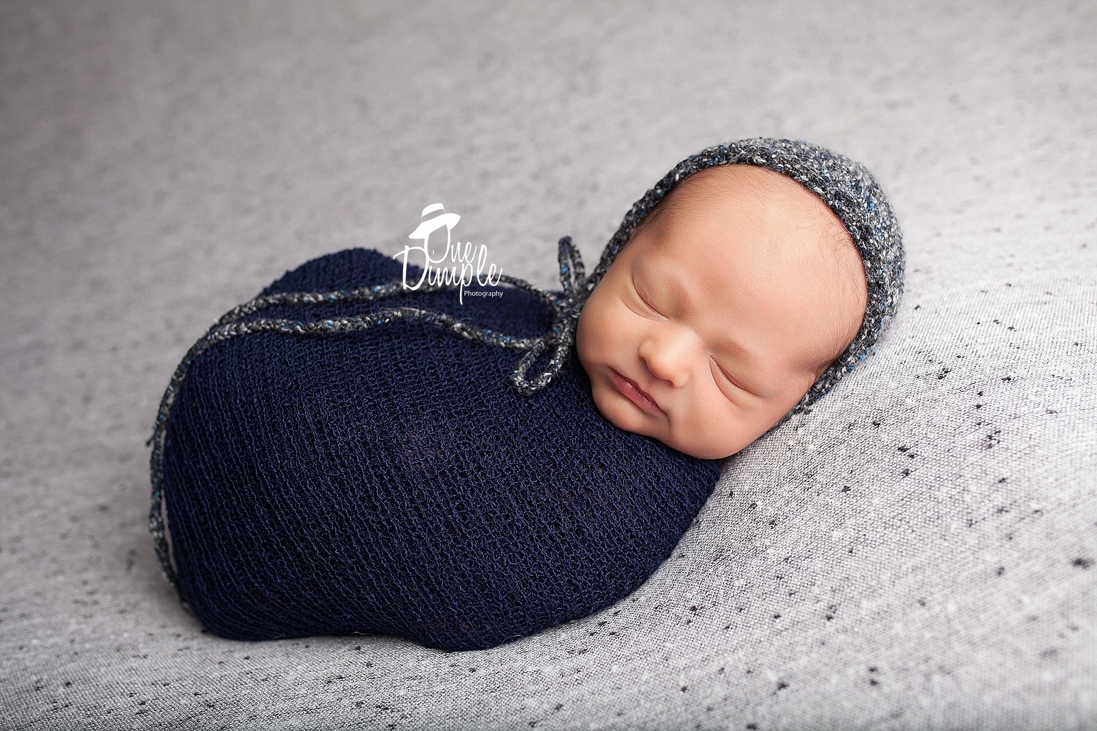 newborn bundled in blue wrap with blue bonnet