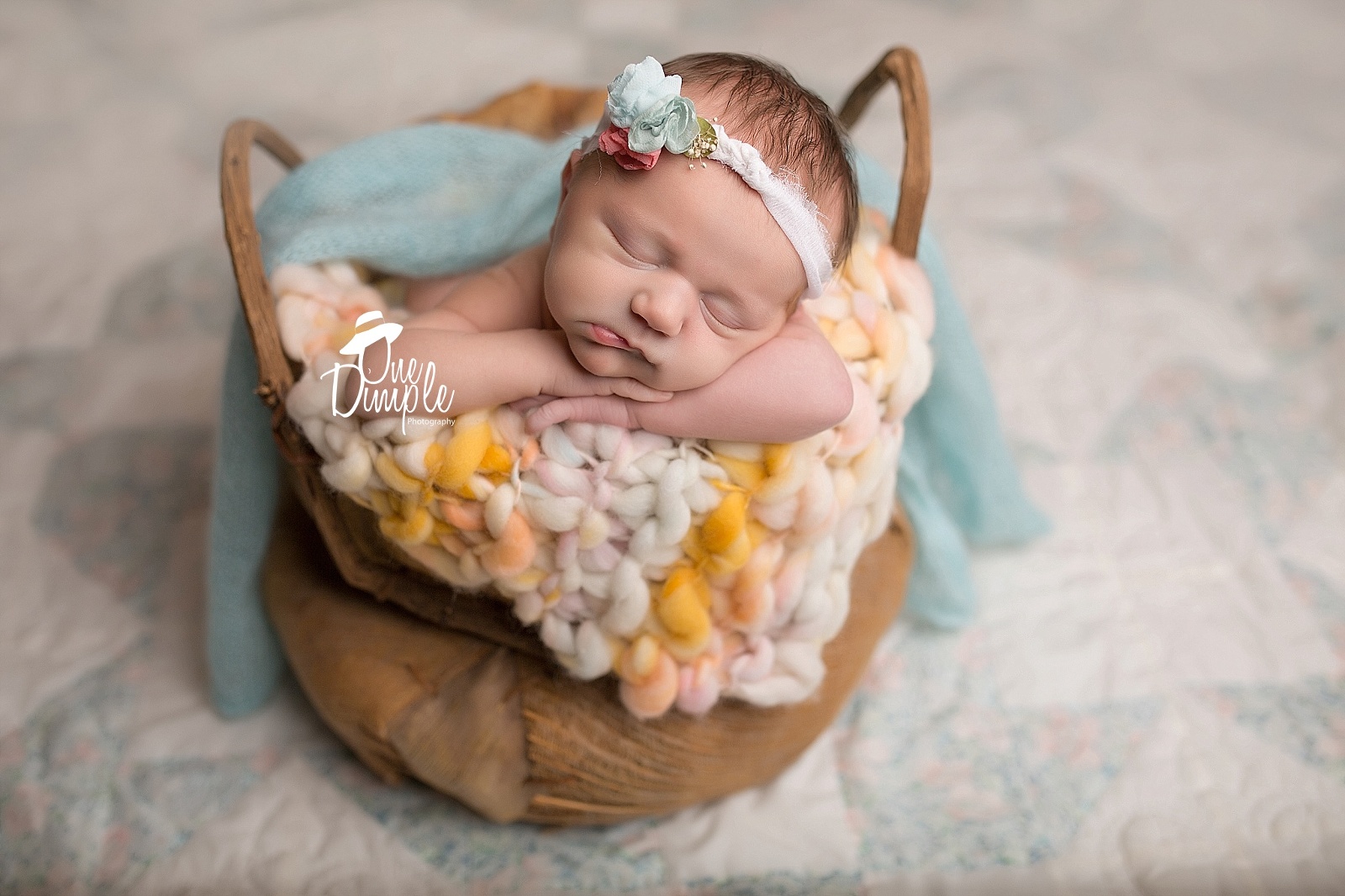 newborn in basket on quilt