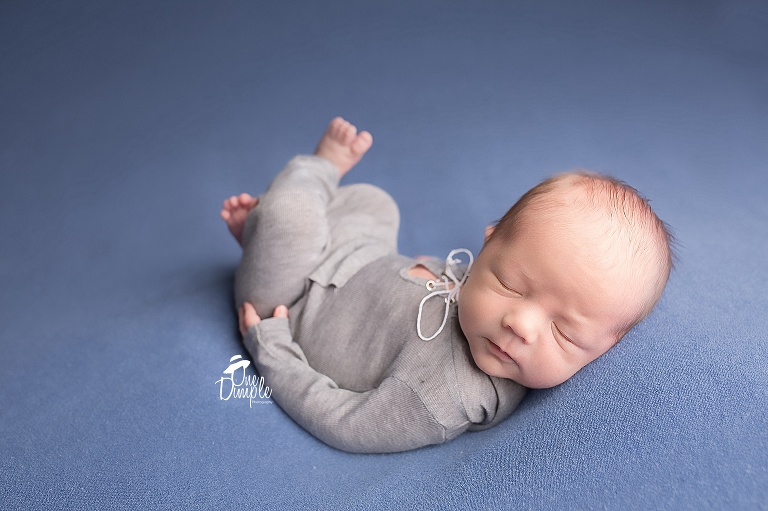 One Dimple Photography DFW In-Home Newborn Photographer Newborn in gray romper in back laying pose