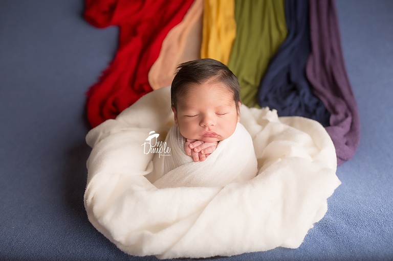 One Dimple Photography is a DFW, Southlake, Trophy Club, Grapevine, Keller newborn photographer. In-Home Newborn Session Rainbow Baby Photo with baby in rainbow cloud